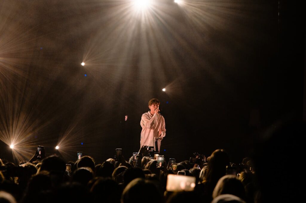 Energetic male singer performing live on stage with a captivated audience.